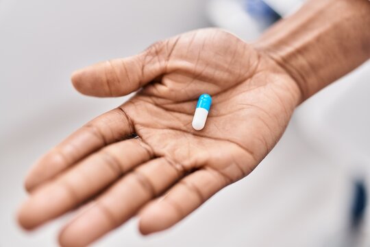 African american woman hand holding pill at clinic