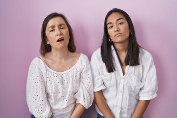 Hispanic mother and daughter together looking sleepy and tired, exhausted for fatigue and hangover, lazy eyes in the morning.