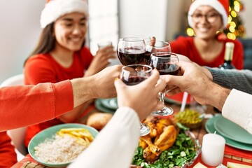 Group of young people smiling happy celebrating christmas toasting with wine at home.
