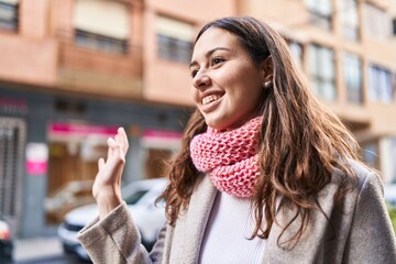 Young beautiful hispanic woman wearing scarf saying hello at street