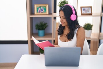 Young hispanic woman sitting on table studying at home