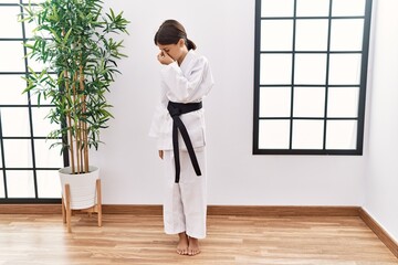 Young hispanic girl wearing karate kimono and black belt tired rubbing nose and eyes feeling fatigue and headache. stress and frustration concept.