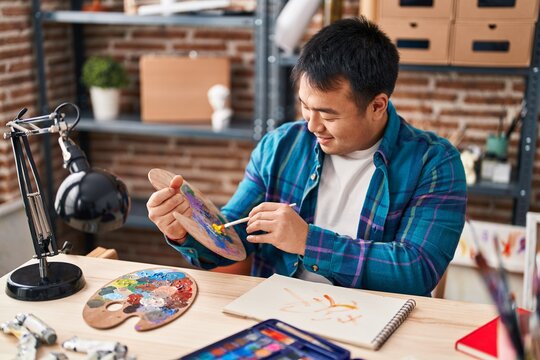 Young chinese man artist drawing on notebook at art studio