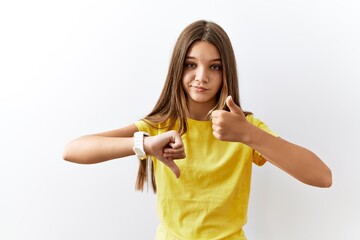 Young brunette teenager standing together over isolated background doing thumbs up and down, disagreement and agreement expression. crazy conflict