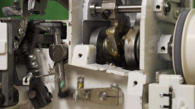 Mechanism of sewing equipment. Close-up. Repair of overlock and sewing machines. Mechanism at work