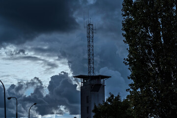 Wieża remizy strażackiej w Ostrowcu Świętokrzyskim , na tle deszcowych , skłebionych chmur .