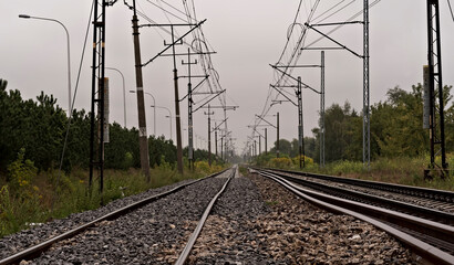 Szyny kolejowe . Widoczne słupy i kable trakcji elektrycznej do napędzania elektrycznych pociągów .