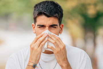 young man with scarf in the street with allergy or cold