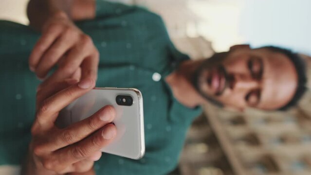 VERTICAL VIDEO: Close-up of the hands of young man using the phone