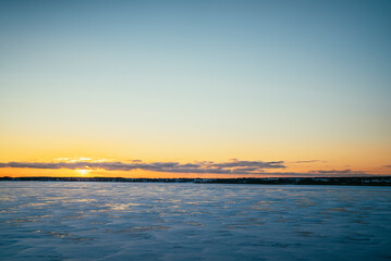 landscape at sunset frozen lake covered with snow in winter on a cold day