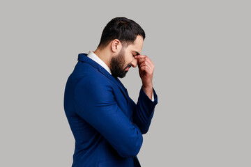 Side view of sad upset unhappy bearded businessman hiding face in hand crying, feeling stressed...