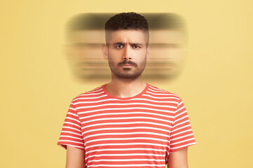 Triple exposure creative portrait of serious handsome bearded man in red t-shirt looking at camera with angry face. Mental health concept. Indoor studio shot isolated on yellow background.