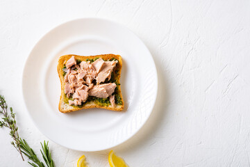 Toast with chimichurri sauce and tuna on a white plate. White background. Minimalistic design. Useful snack.