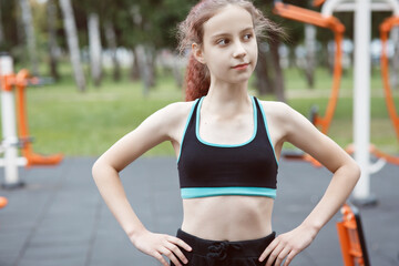 Young sporty active slim girl in sportswear has  workout,  fitness and exercice outdoors, sitting after training or jogging on a sportsground in a park, urban lifestyle health and wellness portrait