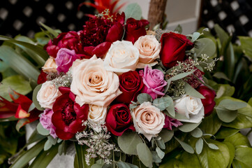 Wedding table floral arrangement of crimson peonies, cream and purple roses and eucalyptus