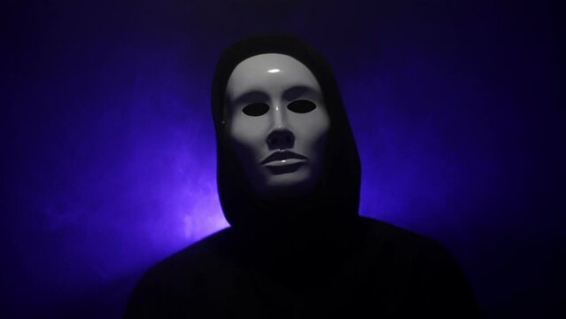 Man wearing mask with hoodie on blue background.
