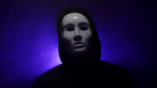 Man wearing mask with hoodie on blue background.