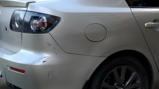 View of a Young man after car crash looking for scratches on his car and calling to insurance comany. Car damage, car crash concept,