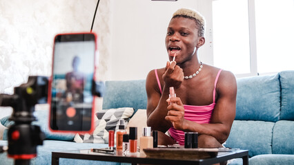 Transgender beauty blogger applying makeup to mobile phone camera
