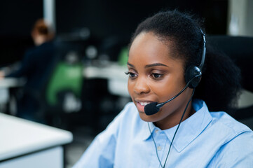 African young woman talking to a client on a headset. Female employee of the call center.