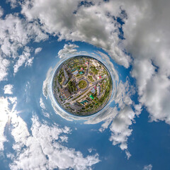 tiny planet in sky with clouds overlooking old town, urban development, historic buildings and...