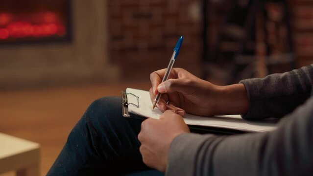 Psychotherapist taking notes on papers and listening to man complaining about marriage. Male counselor writing consultation report on clipboard at couple therapy session. Close up.