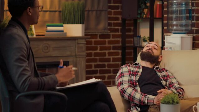 Male psychiatrist listening to man with marriage problems, trying to solve conflict and give counseling advice. Talking to counselor about psychoanalysis at therapy session in office.