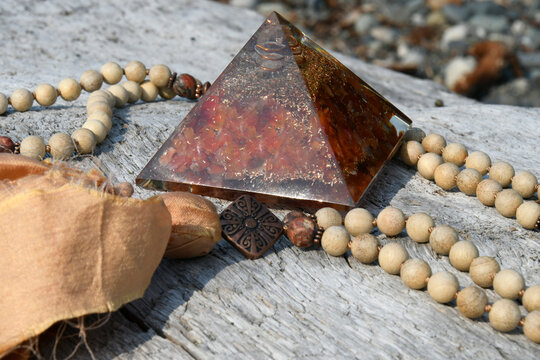 A close up image of a handmade mala necklace with carnelian orgonite pyramid.