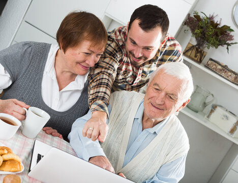 Smiling family watching interesting news and video on Internet on notebook at home