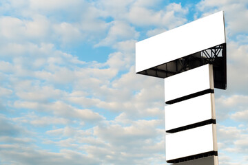 Mock up - four blank white billboards or large advertising displays against blue sky with white...