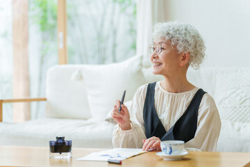 リビングで手紙を書くシニア女性