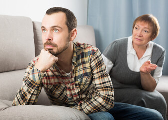Mature mother having disagreement with adult son at home