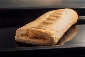 Puff pastry bun with apple jam baking and rising on tray in electric oven - close up view. Homemade bakery, food, cooking and pastry concept