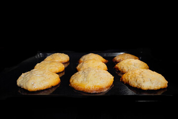 Nine baked homemade crunchy oatmeal cookies on metal sheet in oven - close up front view. Dessert, cookery, baking, gastronomy and food concept