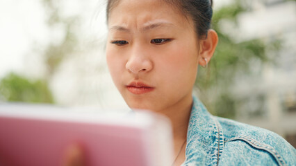 Close up concentrated Asian student girl looking serious learning by heart homework for the next lesson. Young female student diligently studying