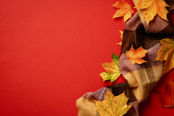 Autumn composition. Plaid with maple leaves on red background. Flat lay, top view, copy space