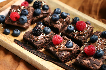 Brownie with berries and chocolate on a wooden board. Homemade vegan brownies.
