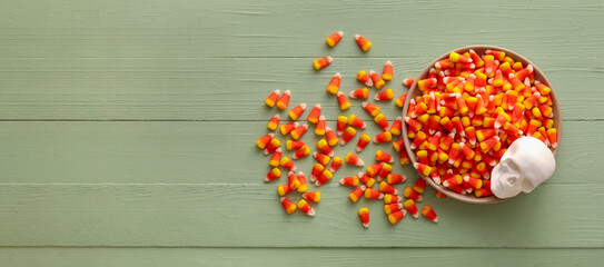 Bowl of sweet Halloween candy corns on wooden background with space for text, top view