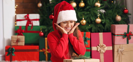 Obraz na płótnie Canvas Cute little girl with gift at home on Christmas eve