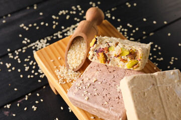 Board with tasty sesame halva on dark wooden background, closeup