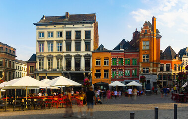 Fototapeta na wymiar Scenic summer view of paved entirely with cobblestones and decorated with colorful facades lively Grand Place, main square in centre of old Belgian city of Mons, Wallonia