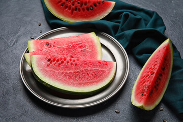 Plate with slices of watermelon and napkin on dark background