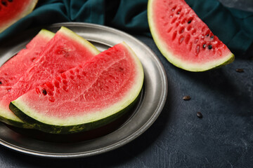 Plate with slices of watermelon and napkin on dark background