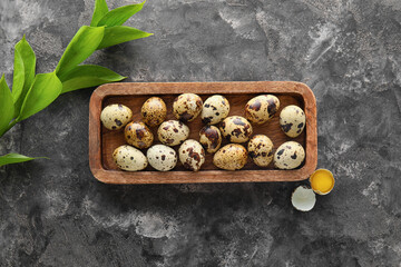 Wooden board with fresh quail eggs on grunge background
