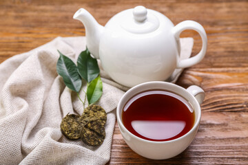Napkin with dry pressed puer tea, cup and teapot on wooden background