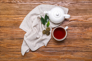 Napkin with dry pressed puer tea, cup and teapot on wooden background
