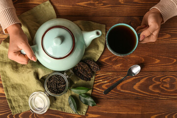 Woman with cup of aromatic puer tea at wooden table