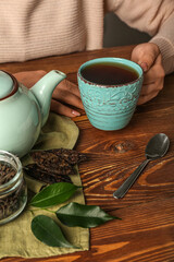 Woman with cup of aromatic puer tea at wooden table