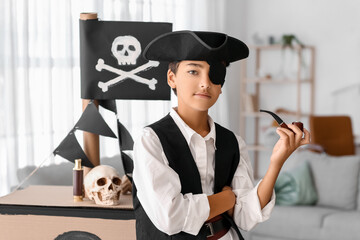 Little boy dressed as pirate with smoking pipe and cardboard ship at home