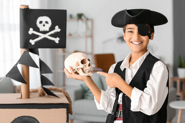 Little boy dressed as pirate pointing at human skull at home